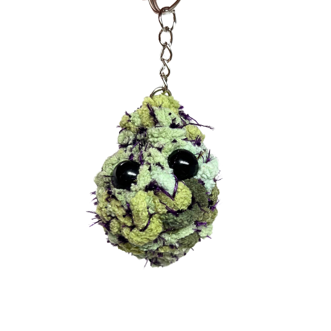 Green and purple plush nug keychain modeled after Granddaddy Purp. Features black eyes and vivid purple stitching. Unique and handmade.