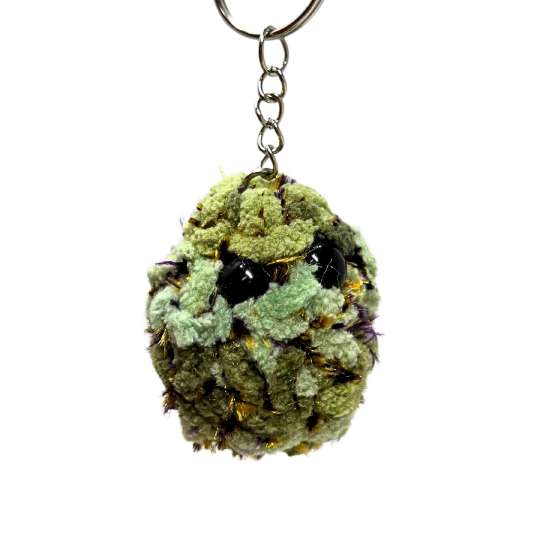 Golden plush nug keychain with hints of purple and orange. Features black eyes and rich texture, inspired by Super Boof flower.